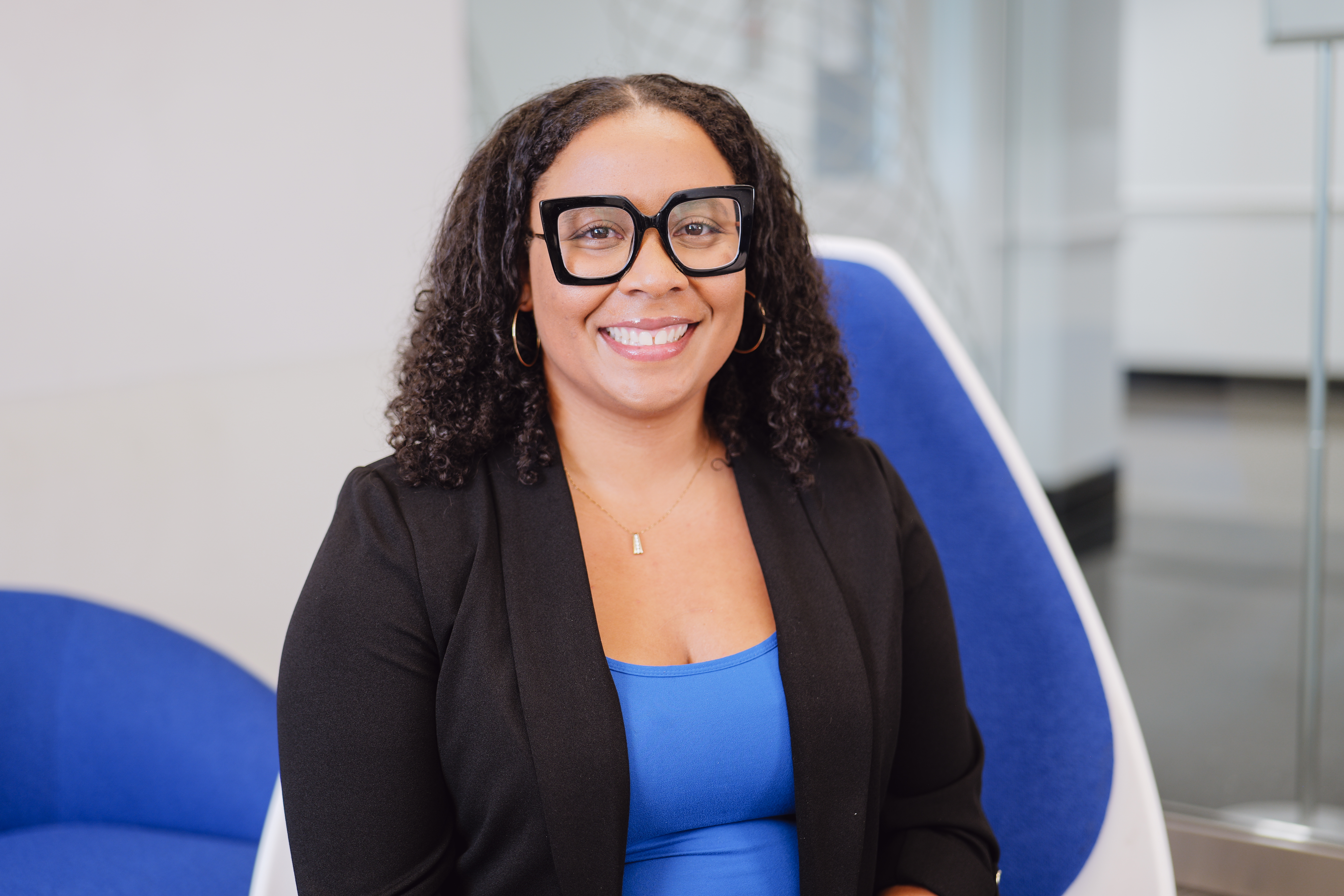 Andrea is seated and smiling at the camera. She has on professional attire