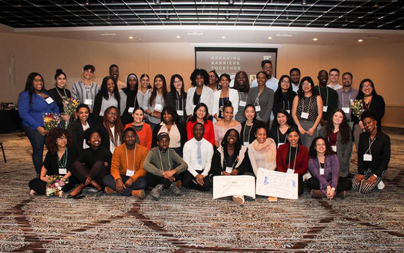Group of students sitting and standing together in the ballroom of the Syracuse Marriot at the Inaugural NSYOP Student Conference Breaking Barriers Together