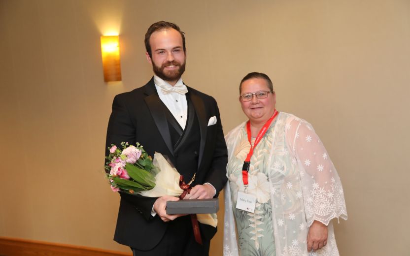 Christopher Mahn is pictured on the left holding flowers and a award