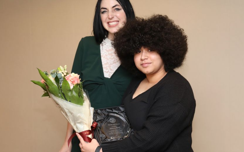 Jennessa Perez is receiving her award from a staff member.  She is holding a bouquet of flowers.