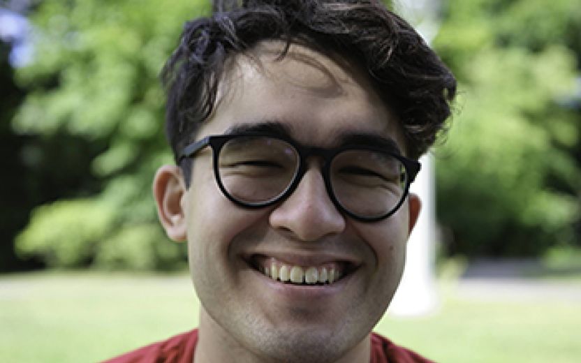 John Starr is smiling at the camera. He is outside and has glasses on a red shirt