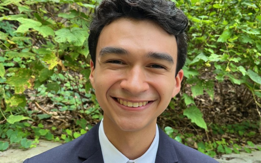 Rafael Montan is outside and smiling at the camera, he has a business suit on