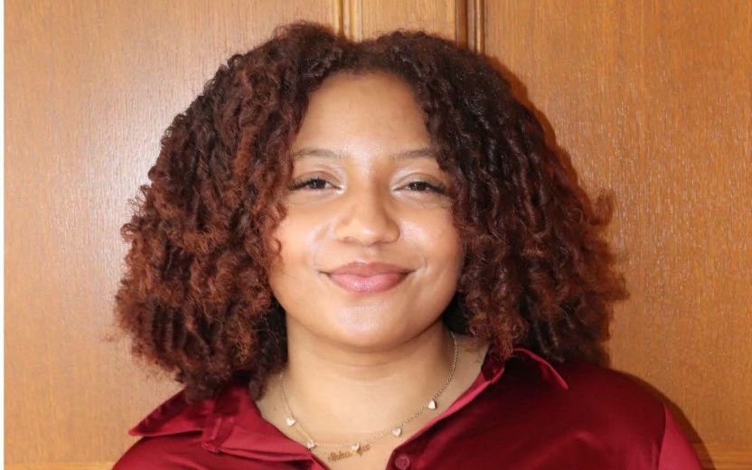 Sukanya Fergurson is smiling at the camera. She has a red button-down shirt on