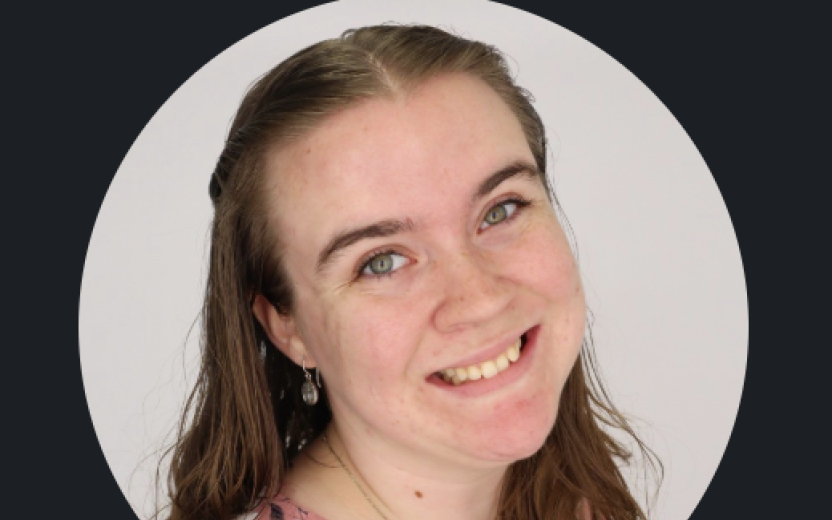 Jenna Leslie is smiling at the camera. She has on a pink shirt