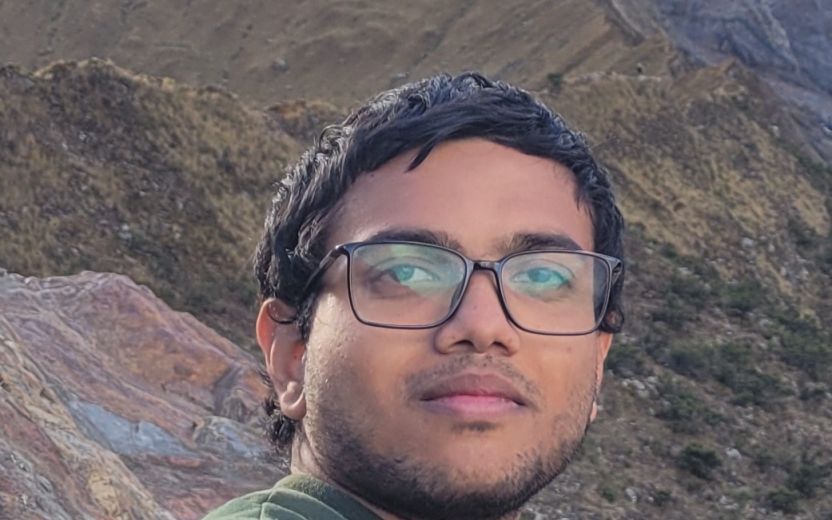 Sarvesh Prabhu is outside in the mountains and looking at the camera