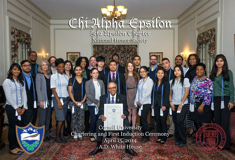 group of students and staff standing in a great hall at the AD White House on Cornell’s campus with the most honorable Dr. Elbert Saddler holding Cornell’s Chi Alpha Epsilon’s Charter.
