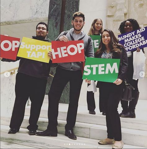 5 students holding signs for HEOP, TAP, STEM, BUDY AID, and CSTEP on the steps of the Legislative Office Building in Albany, NY as part of Student Aid Alliance’s Advocacy Day Efforts