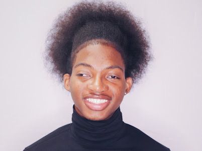Triston Edwards is smiling at the camera. He has on a black turtleneck