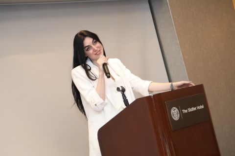 Shanna Leipzig is standing at a podium speaking at an event