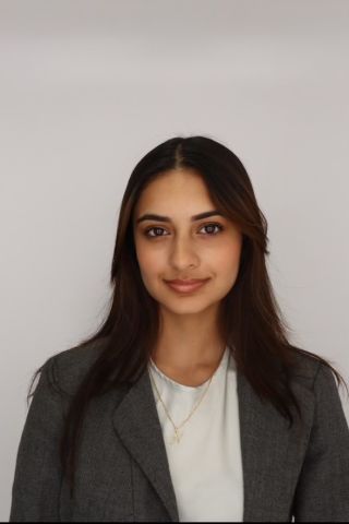 Nailah Alladeen is smiling at the camera and wearing a business suit