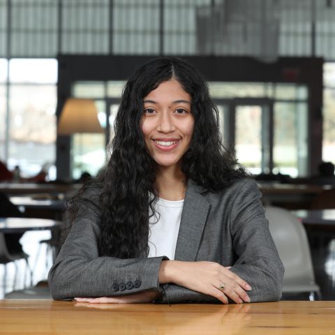 Paula Blanco Ortiz is smiling at the camera with her arms crossed and seated