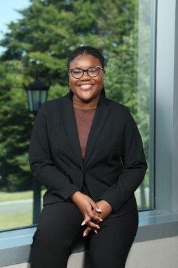 Jada Vyphuis is sitting down and smiling at the camera. She is wearing business professional clothes