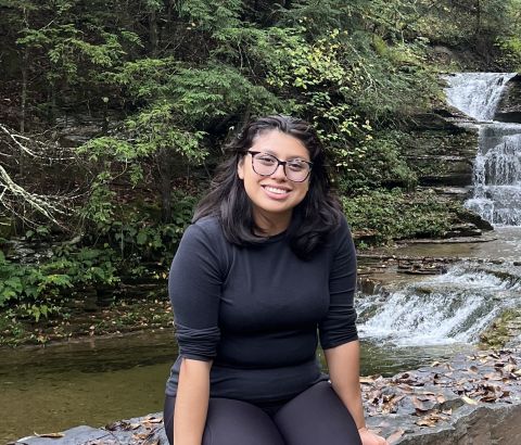 Maritza Reyes is sitting by a waterfall and smiling at the camera