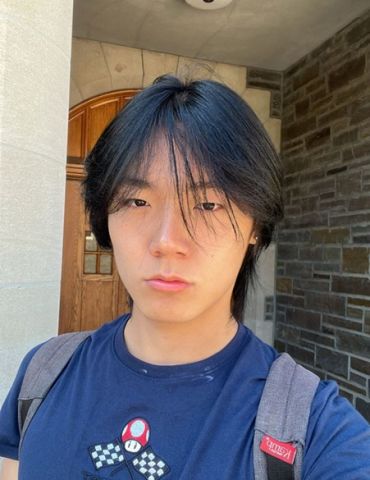 Andy Zong is looking at the camera. He has on a blue shirt and backpack