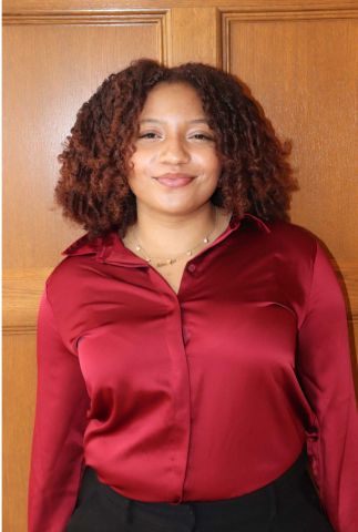 Sukanya Fergurson is smiling at the camera. She has a red button-down shirt on