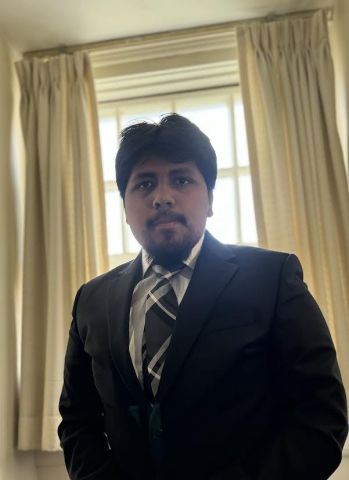 Yair Sanchez-Arenas is looking at the camera with a blazer and tie on